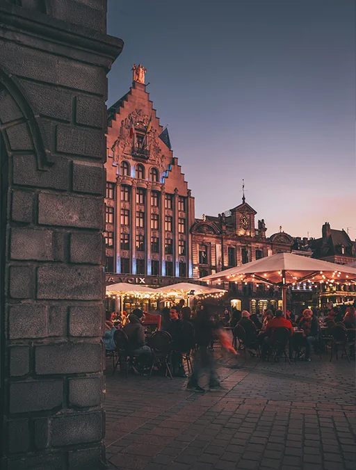 Grand Place de Lille au crépuscule, terrasse illuminée, ambiance festive.